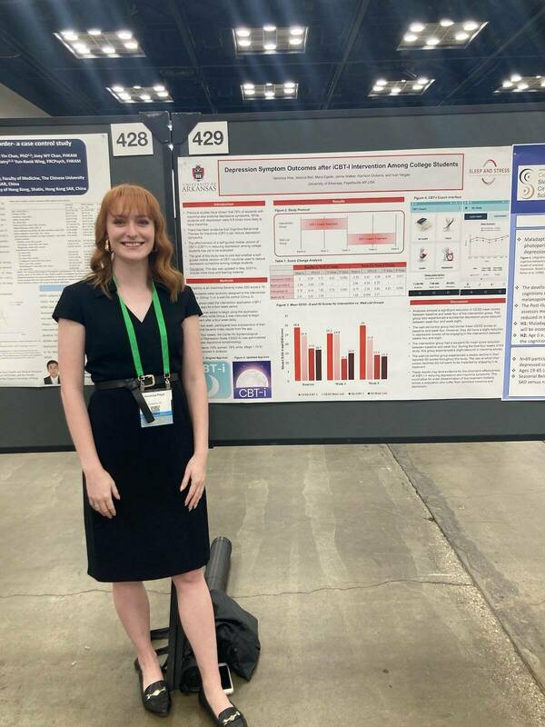 Veronica standing in front of her poster at a conference.