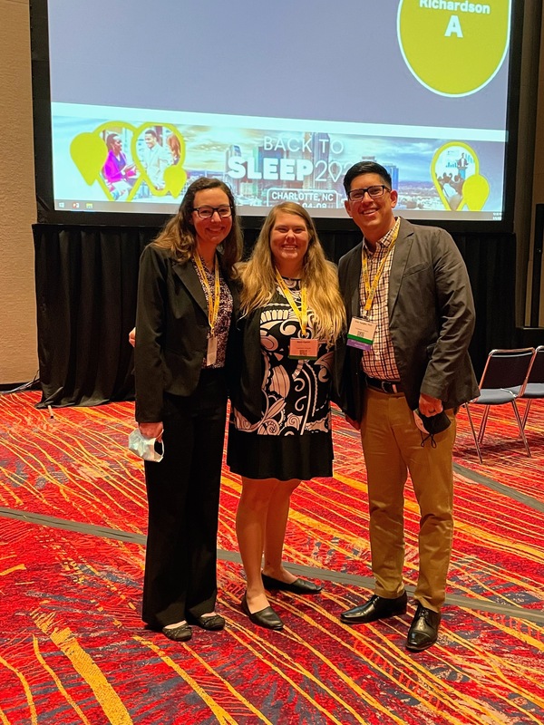 Lab members standing together ina  conference hall. 
Presenting from left to right: Jamie, Mara, and Dr. Vargas.