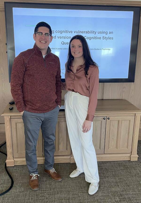 Dr. Vargas standing with an undergraduate student, a white cisgender woman, during her honors thesis defense.