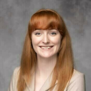 Square headshot of Veronica, presenting as a caucasian female with red hair and a tan suit jacket.